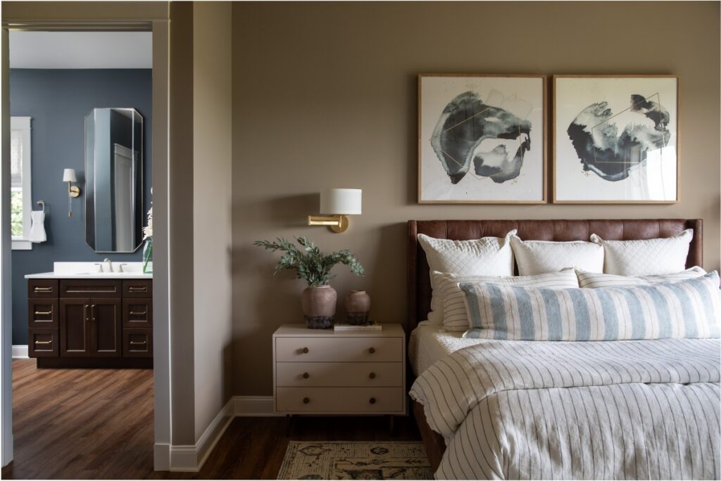 Primary bedroom with upholstered bed and adjoining modern bathroom vanity.