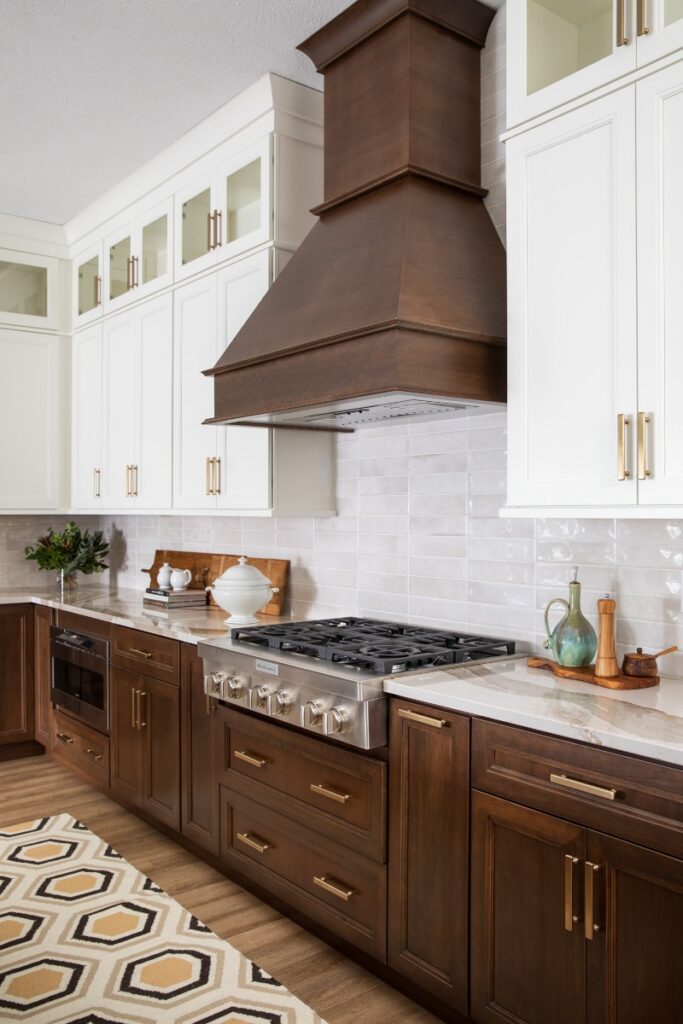 Luxury kitchen with white cabinets, dark wood range hood, and gas cooktop.