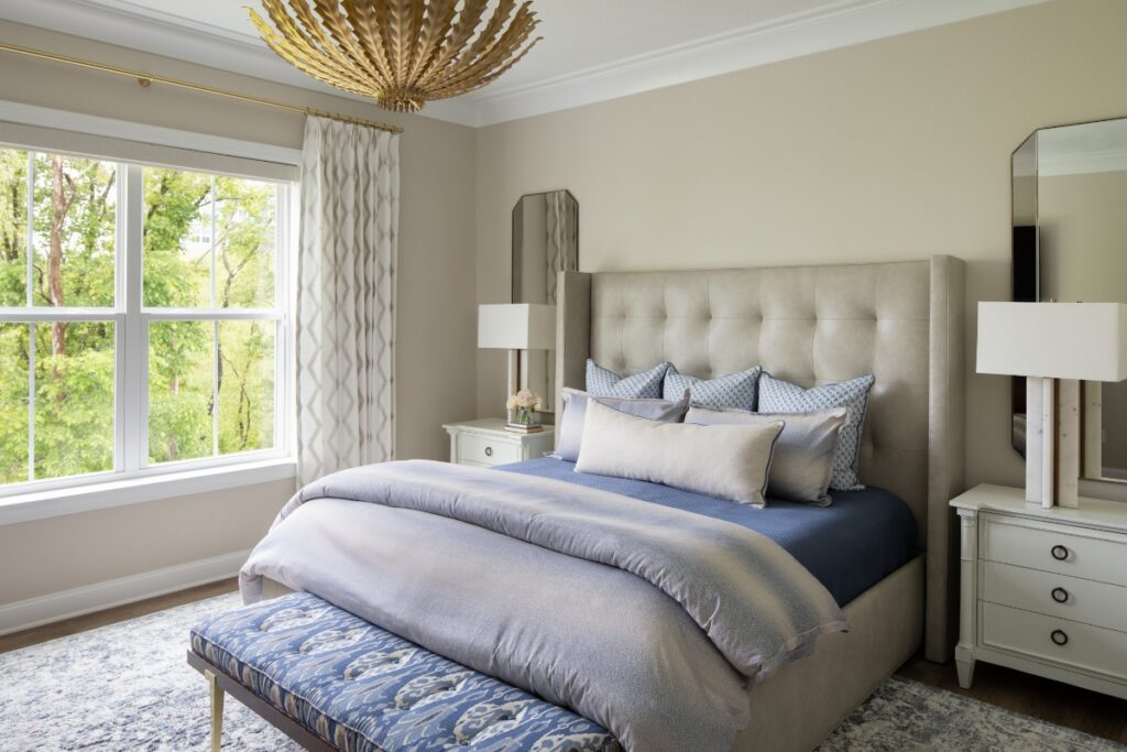 Serene Pittsburgh primary bedroom with tufted bed, blue bedding, and statement ceiling light.