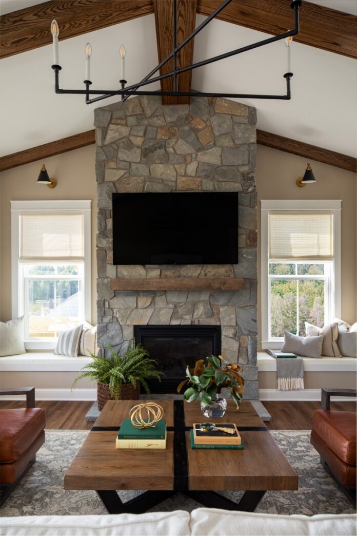Modern Pittsburgh living room with stone fireplace, vaulted wood beams, and black chandelier.