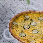 A white ceramic tray with a zucchini quiche inside in a golden color.