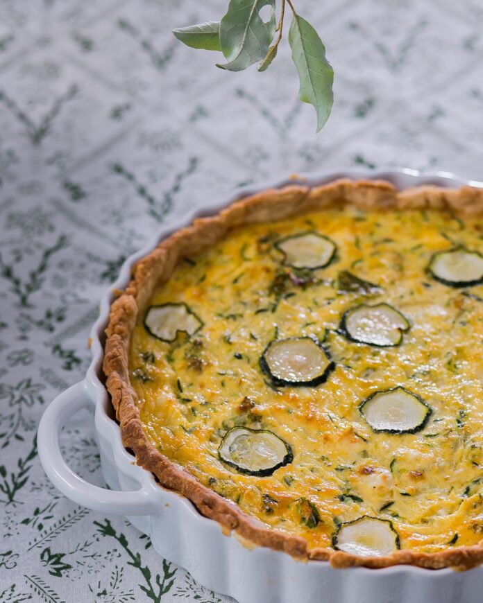 A white ceramic tray with a zucchini quiche inside in a golden color.