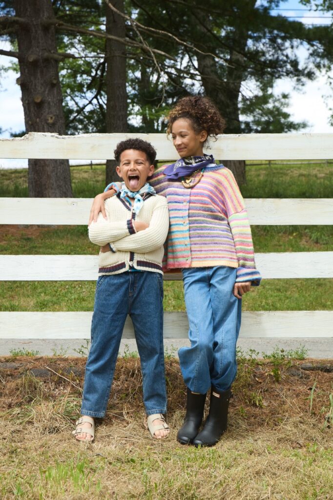 Kids in fall fashion in Pittsburgh near a white fence.