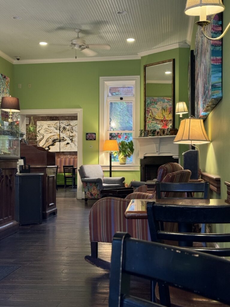Cozy cafe interior with green walls, comfortable seating, and artwork, possibly in Pittsburgh.