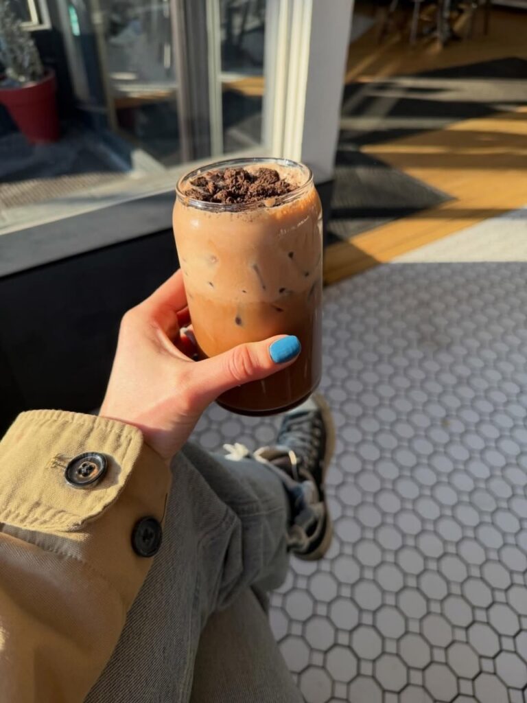 Person holding iced mocha with crushed cookies, Pittsburgh coffee drink