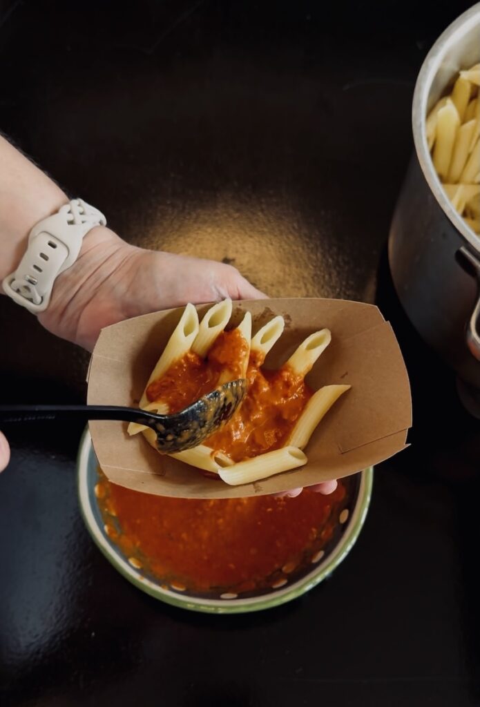 Penne pasta with vodka sauce being served in a paper boat