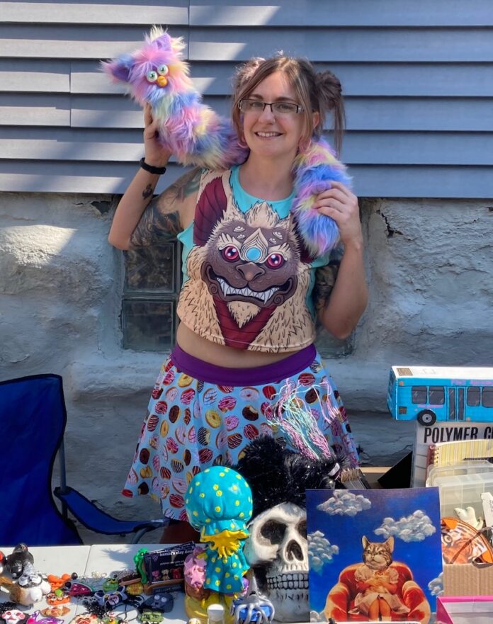 Bloomfield Sidewalk Sale TABLE Magazine Woman at Bloomfield Sidewalk Sale with colorful toys and art