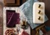 Calming Interior Design & Style Ideas from Pittsburgh’s Experts Davin Interiors jewel-toned flat lay featuring marble, rich textiles, tassel trims, and a brass pear.