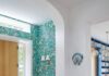 How to Make Decorating Decisions You Won’t Regret: Smart Ideas From a Pittsburgh Interior Designer An entryway featuring an arched doorway, natural light hardwood floors, vibrant green botanical wallpaper on an accent wall, a light wood front door with glass side panels, and a console table with a potted fern.