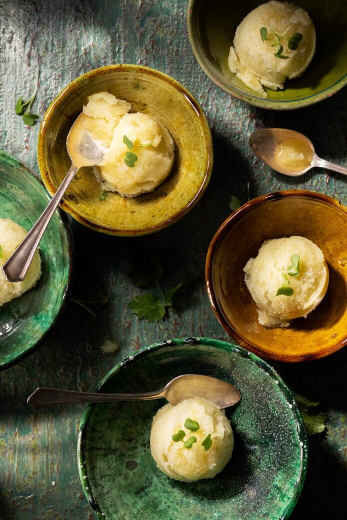 Scoops of green chile lime granita garnished with micro cilantro in small rustic ceramic bowls.