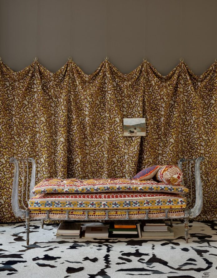 Ornate daybed with patterned cushions in a room with bold, patterned drapery.