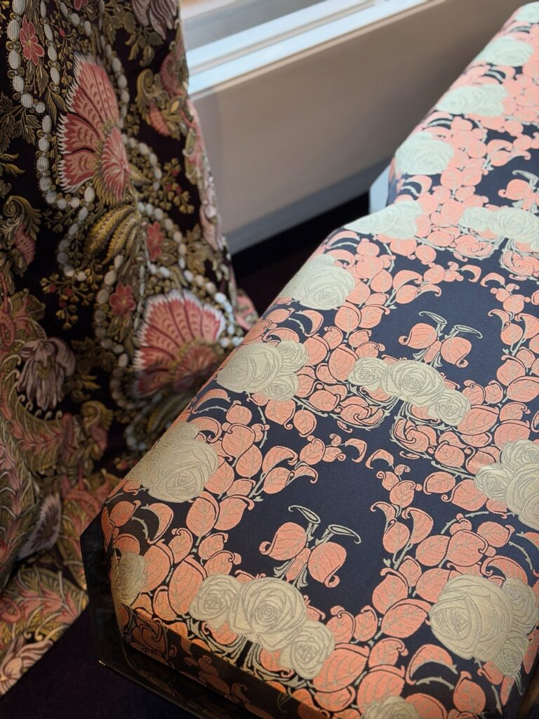 Art Nouveau floral fabric pattern in coral and gold on navy.