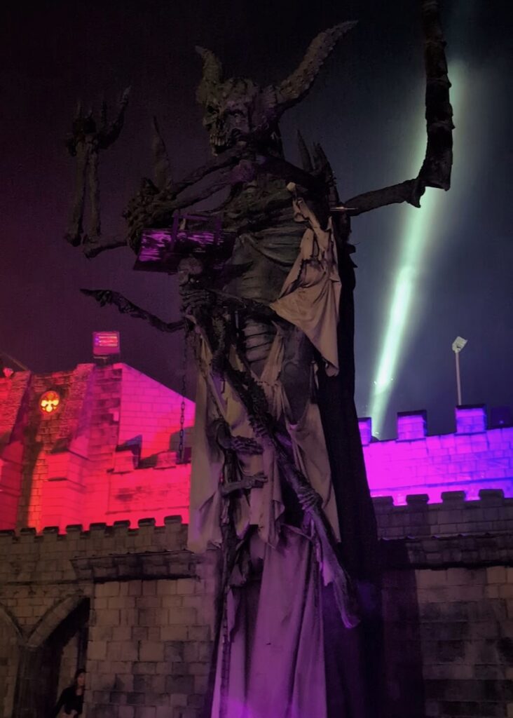 Scary skeleton figure at Hundred Acres Manor, lit with pink and purple lights.