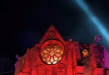 Hundred Acres Manor Guide: Tickets, How Scary Is It & Insider Tips Scary Hundred Acres Manor facade at night with red and blue lights, offering tickets.
