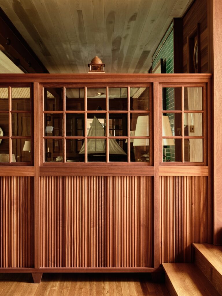 Custom wood partition wall with glass windows separating living spaces over hardwood floors.