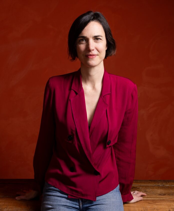 Katie Brook Quantum Theatre Artistic Director TABLE Magazine Katie Brook, new Artistic Director of Quantum Theatre, in a red blazer.