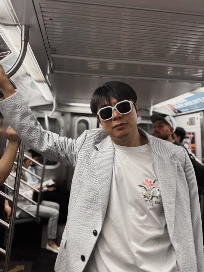 Pianist Lang Lang in a subway car, wearing a blazer and sunglasses.