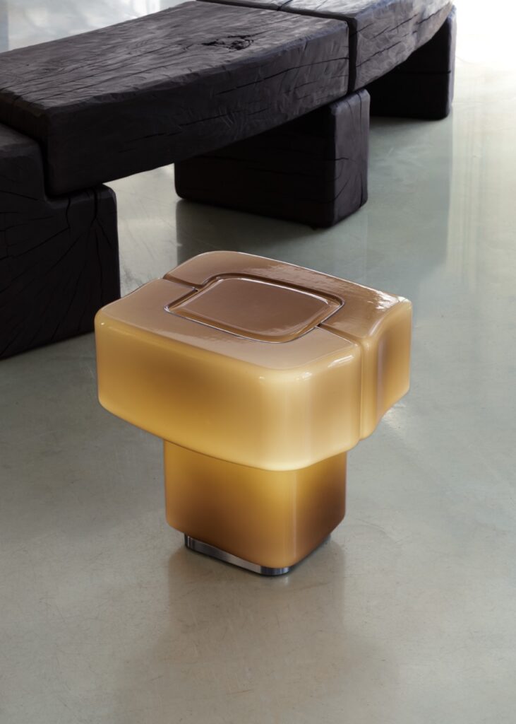 Illuminated amber table lamp with textured dark wood bench
