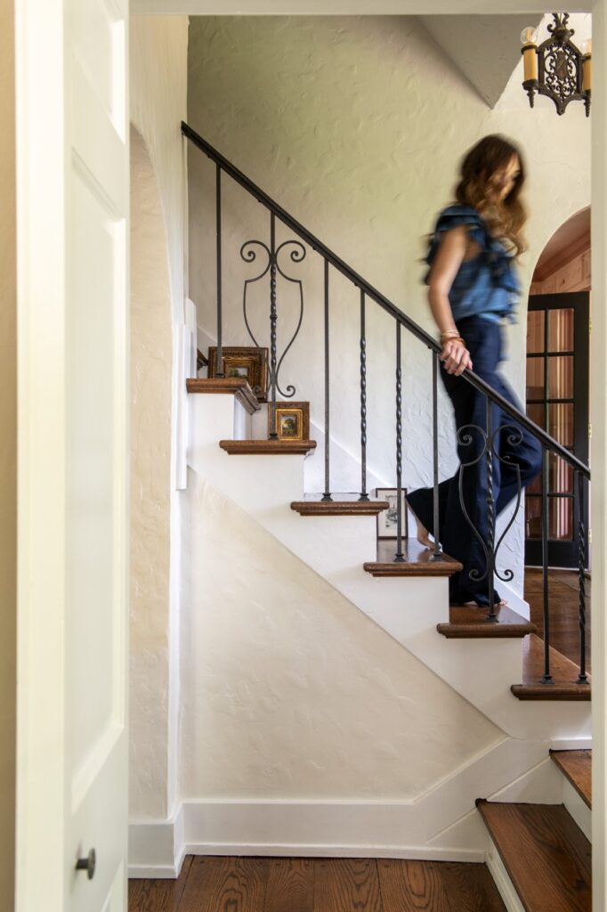 Woman descends stairs in a Mt. Lebanon cottage with decorative railing.