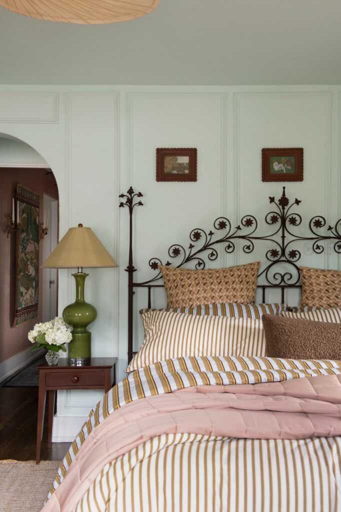 Fairy tale cottage bedroom with striped bedding and wrought iron headboard