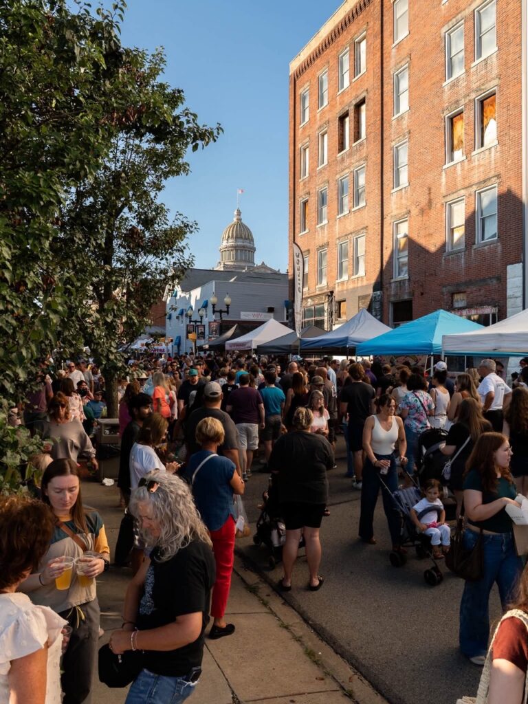 Crowded street market at dusk with food vendors and people enjoying autumn night markets in Pittsburgh.