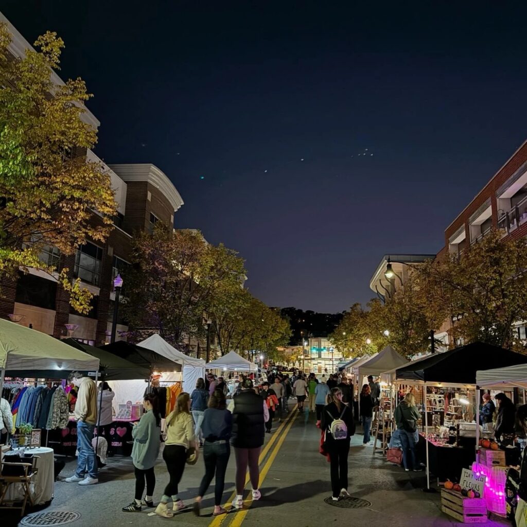 Pittsburgh autumn night market with tents, vendors, and people shopping