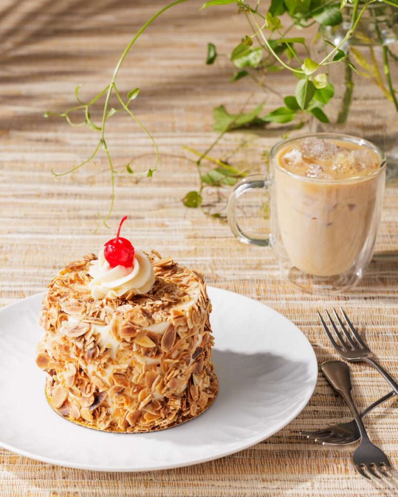 Almond cake with cherry and iced coffee on a wooden table
