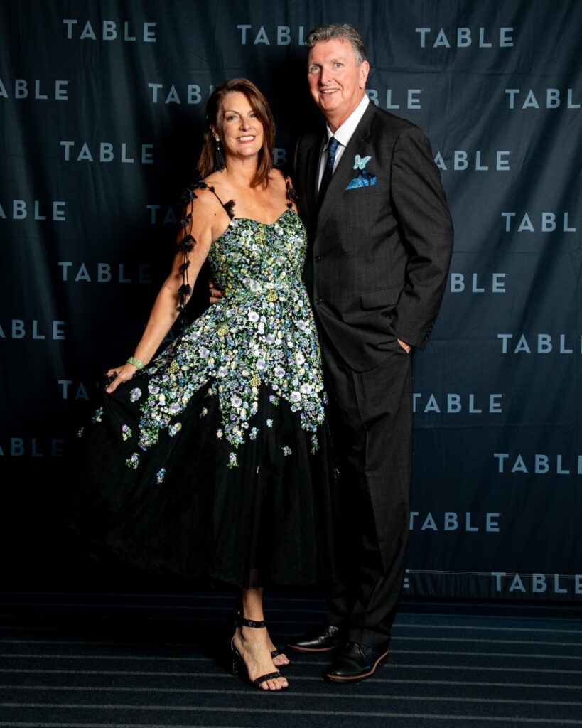 Couple posing in front of TABLE backdrop at a formal event