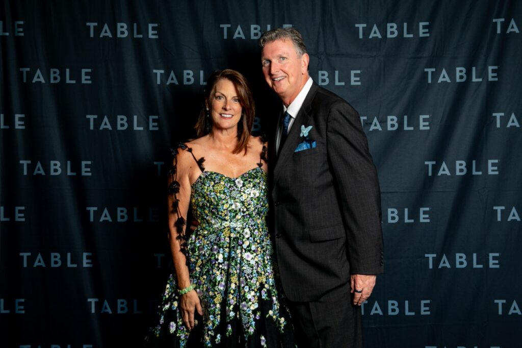 Couple posing in front of a "TABLE" backdrop at an event.