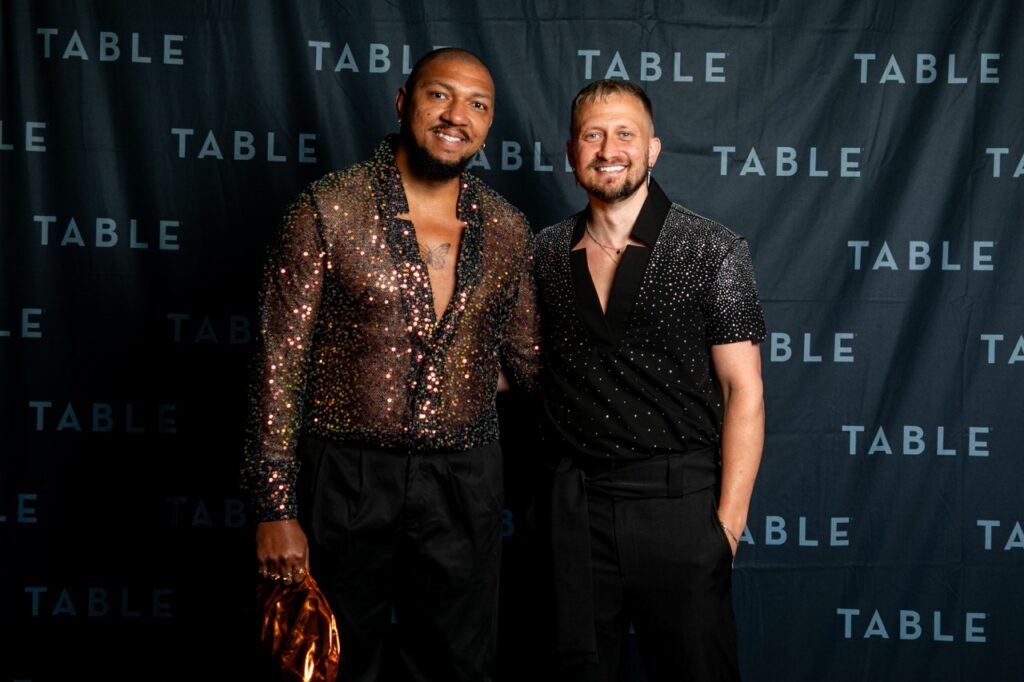 Two men in sparkly shirts pose for a photo at a TABLE event.