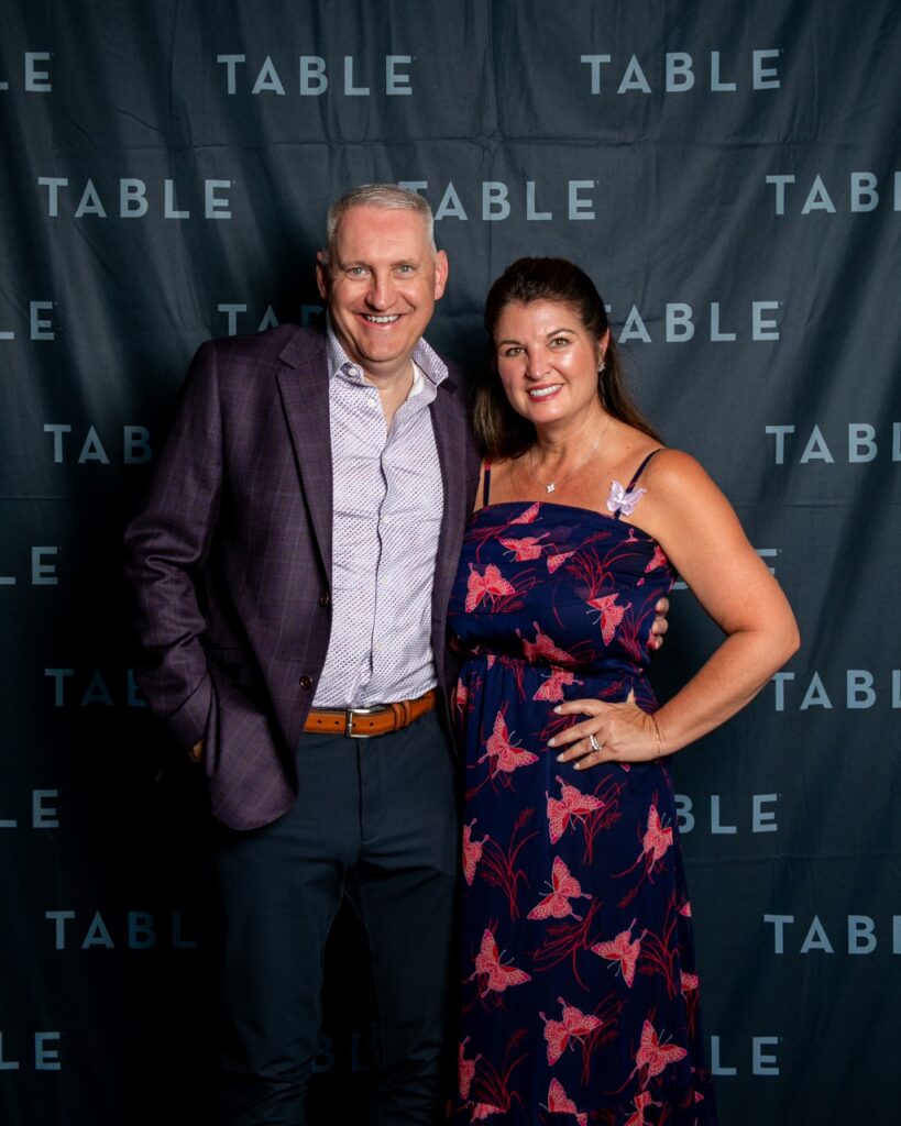 Man in suit and woman in butterfly dress pose at TABLE event