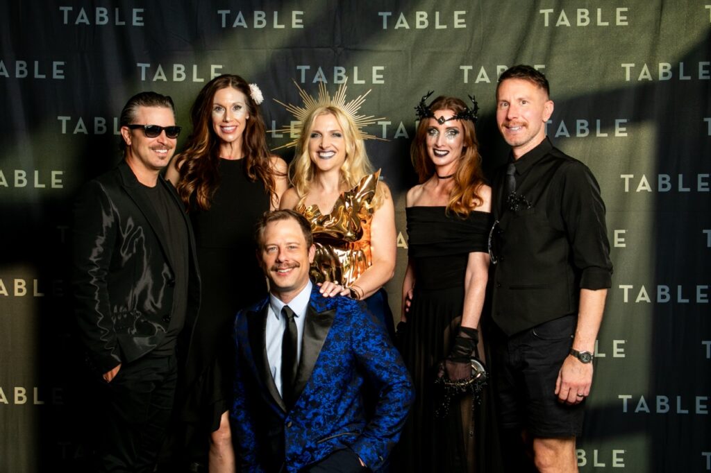 Group of six people in formal and costume attire posing for a photo at an event.