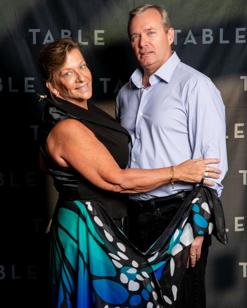 Couple posing in front of a black backdrop with "TABLE" logo