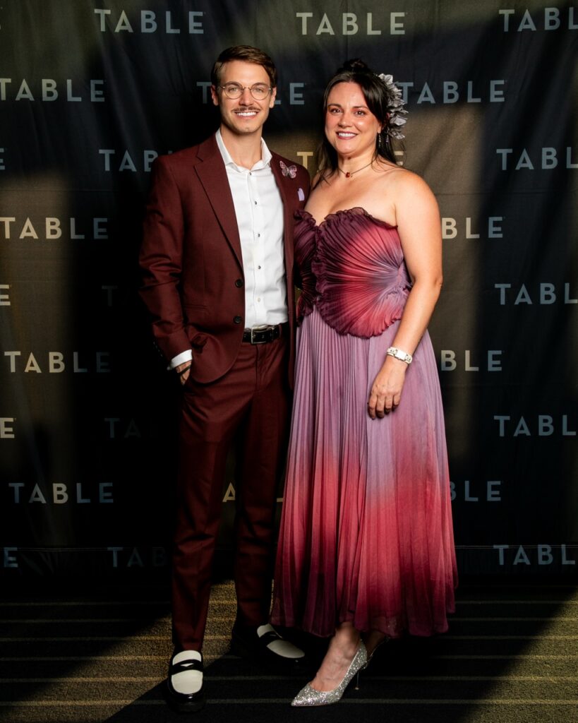 Man in maroon suit and woman in ombre dress at TABLE event