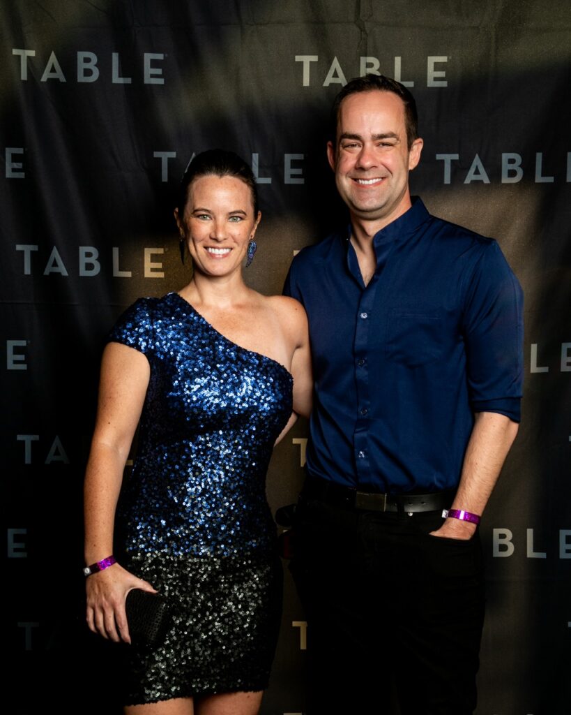 Couple poses for a photo at a TABLE event, smiling at the camera.