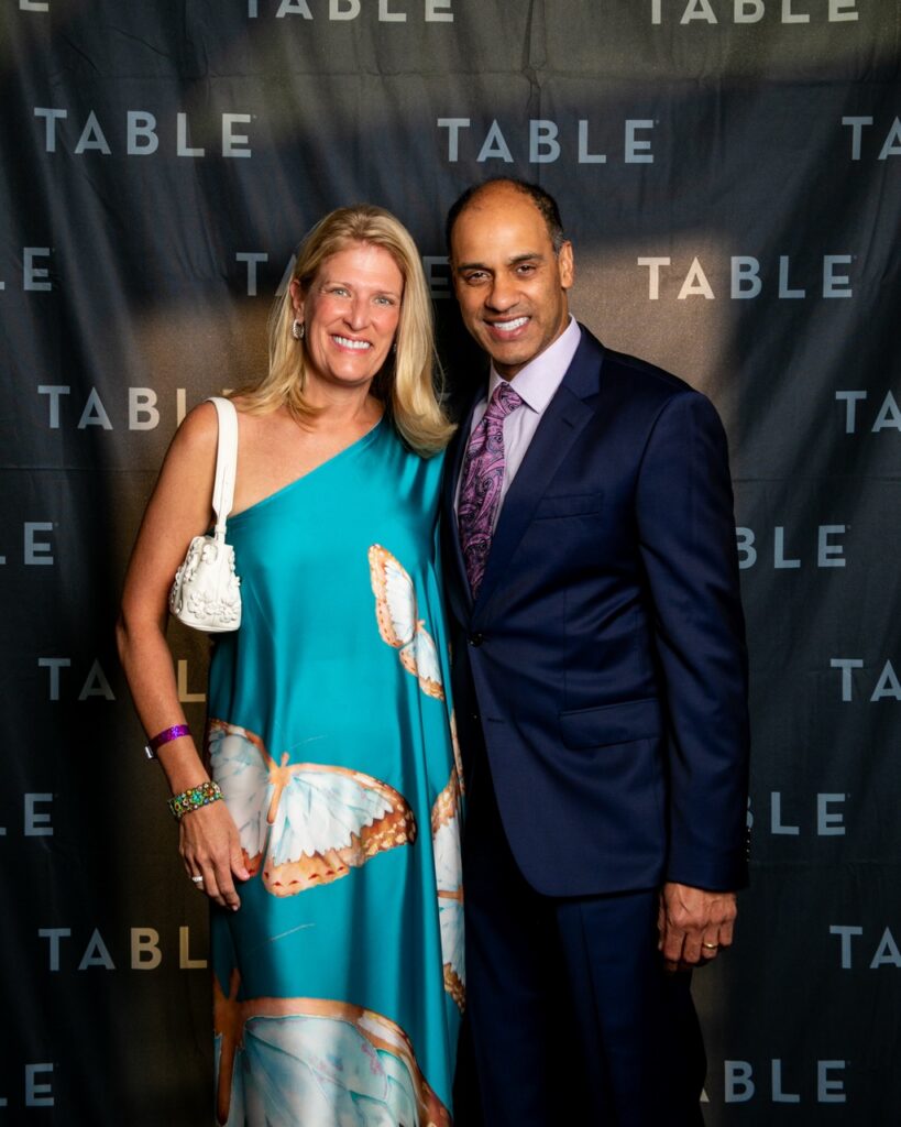 Couple poses at TABLE event, woman in butterfly dress, man in suit.