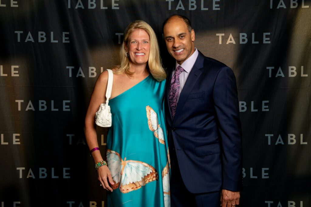 Couple posing in front of a "TABLE" backdrop at an event