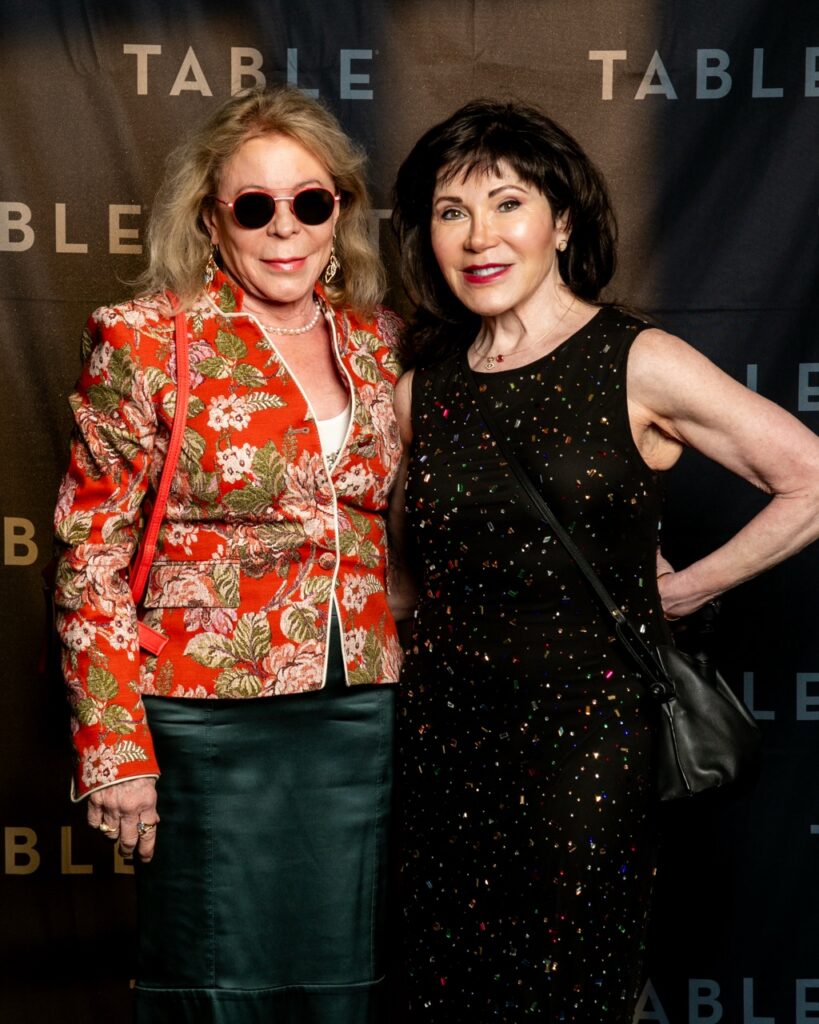 Two women posing for a photo at an event with "TABLE" logo in the background.