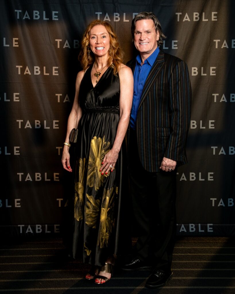 Couple posing in front of a "TABLE" backdrop at an event
