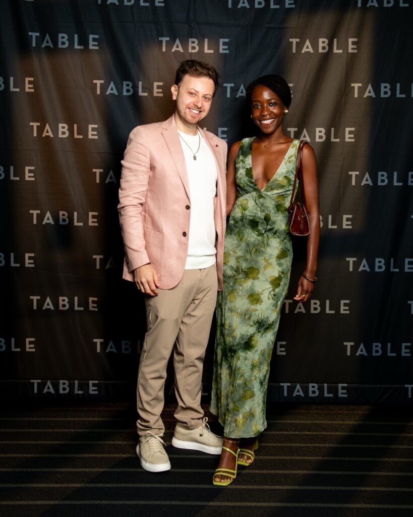 Couple posing in front of a "TABLE" backdrop at an event