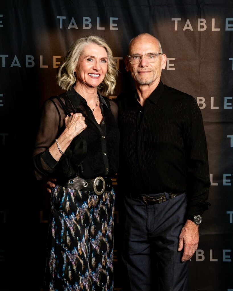 Couple posing for a photo in front of a TABLE backdrop