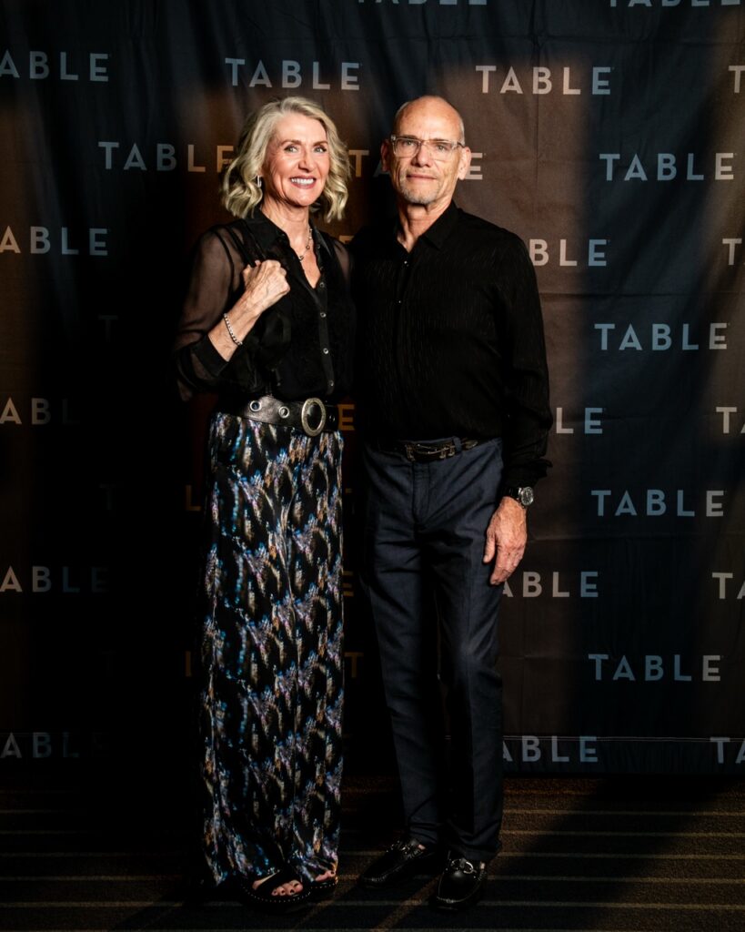 Couple posing in front of a "TABLE" branded backdrop at an event.