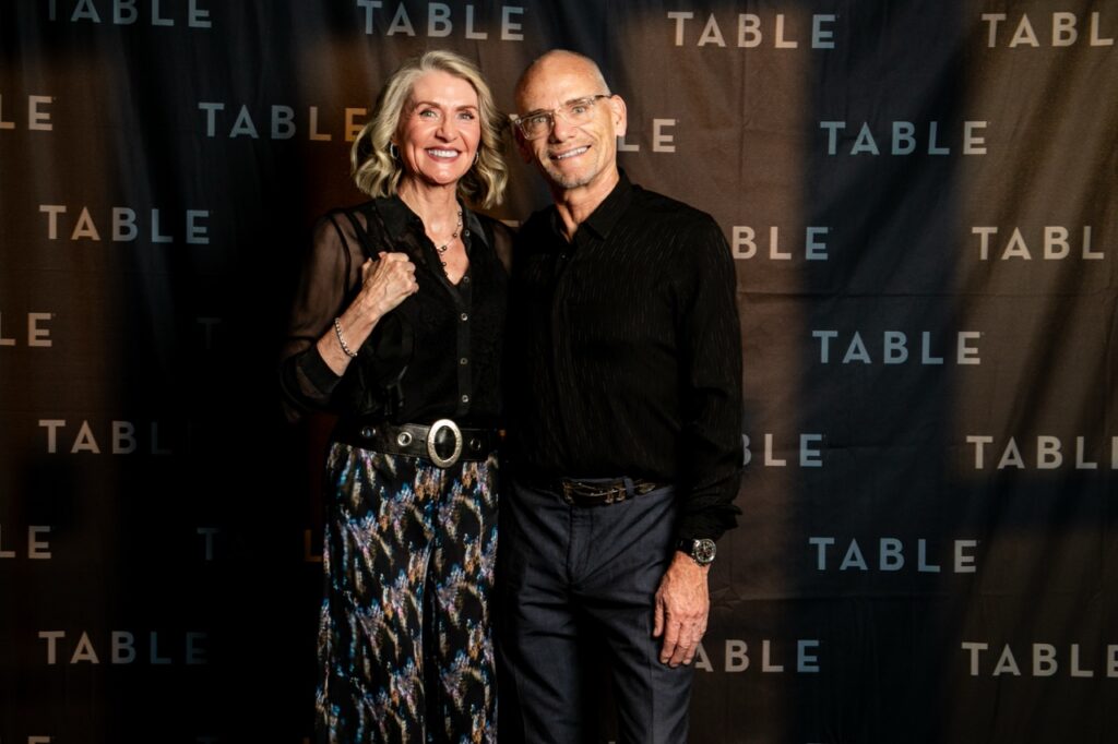 Couple posing in front of a "TABLE" branded backdrop at an event.