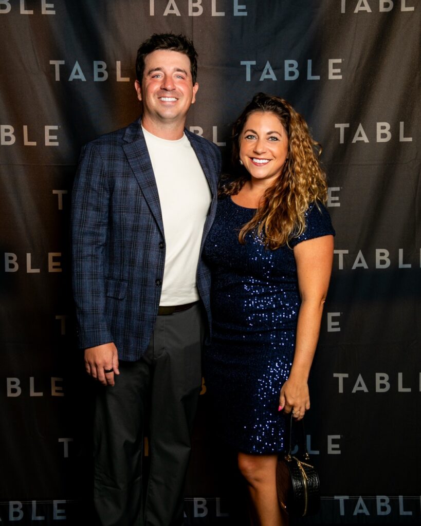 Couple posing in front of a TABLE backdrop