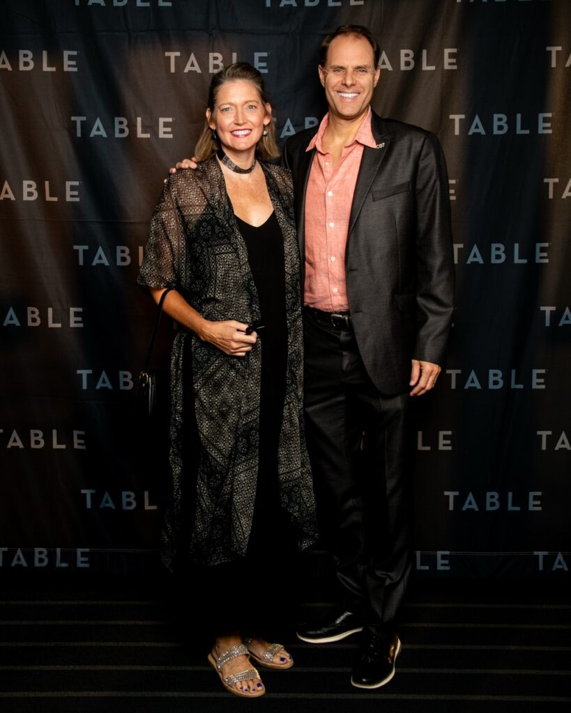 Couple posing for photo at TABLE event, man in suit, woman in dress and shawl