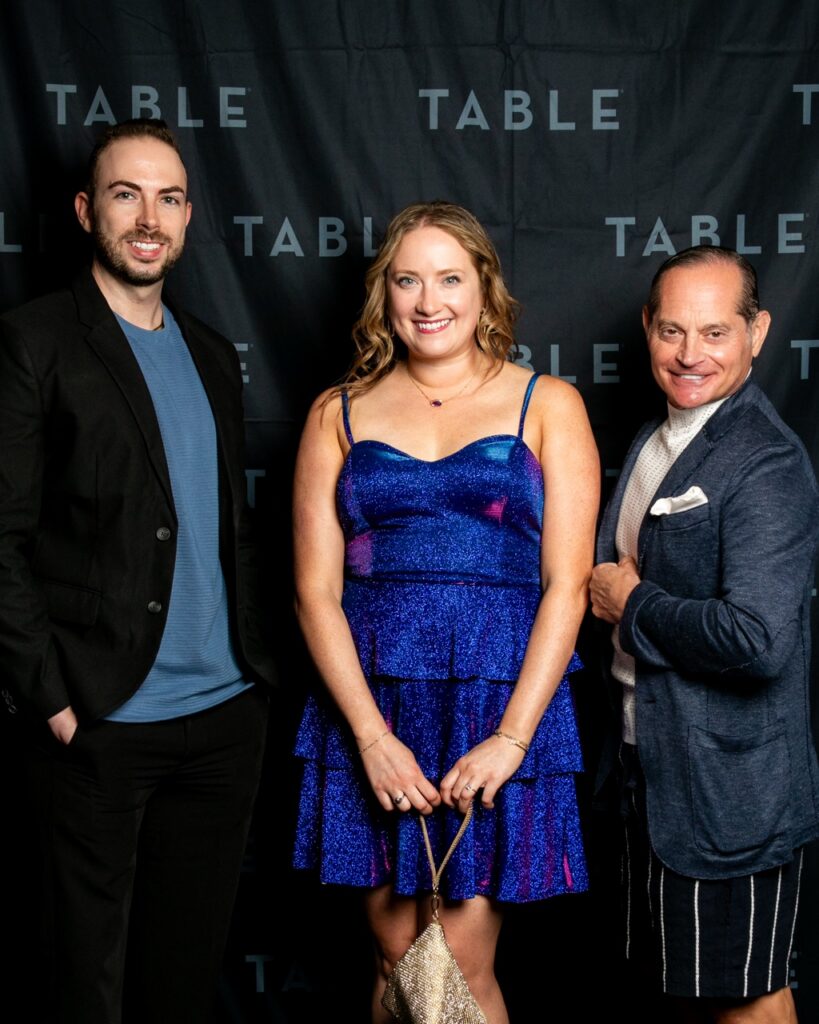 Three people posing for a photo with "TABLE" logo backdrop