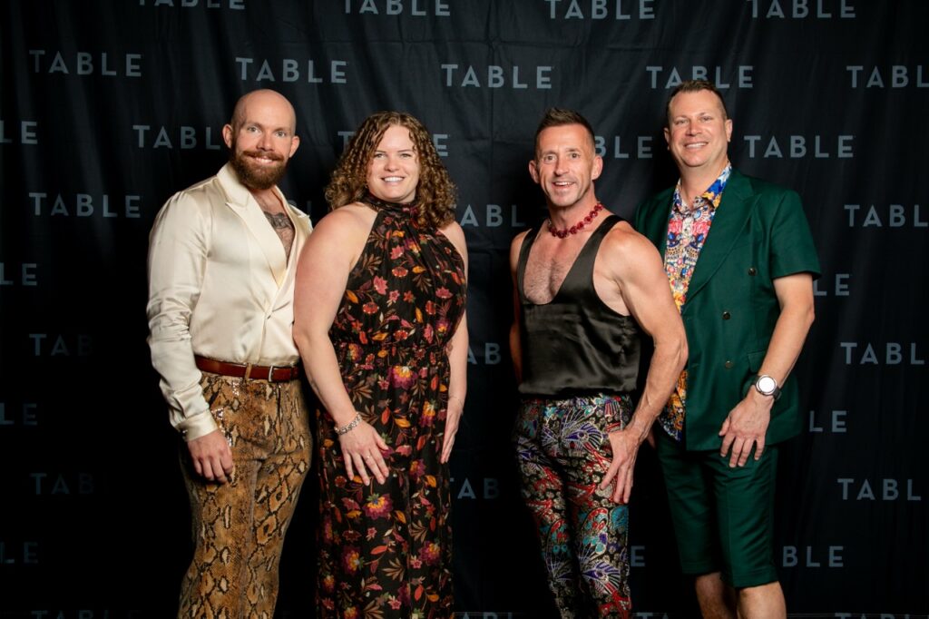 Four stylish individuals pose for a photo in front of a backdrop with the word "TABLE" repeated.