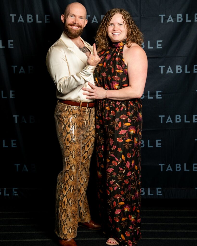 Couple posing in front of a "TABLE" backdrop at an event