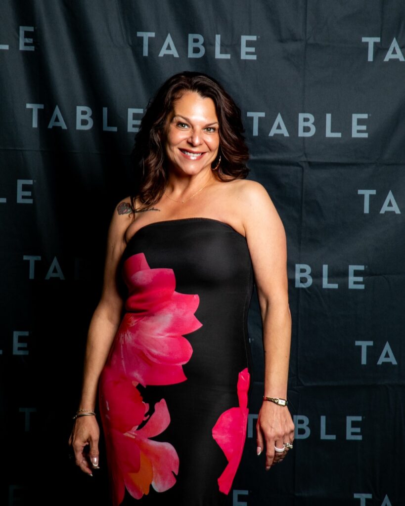 Woman in a strapless dress with a floral print smiling at the camera