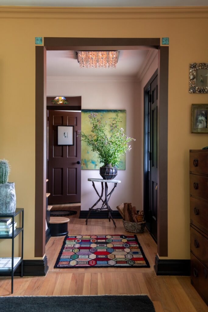 Entryway featuring twig table, floral arrangement, geometric runner rug, and dark brown wood trim.